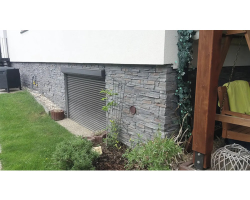 Exteriér domu s kamennou fasádou, okenními roletami a zahradou