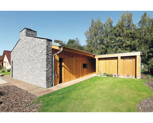 Moderní zahradní domek s dřevěným obkladem, kamenným komínem a trávníkem