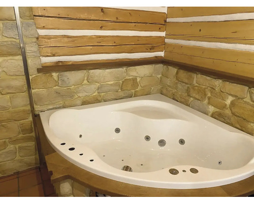Rohová vana s vířivkou v koupelně s dřevěnou stěnou a kamenným obkladem