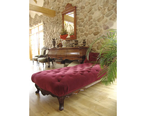 Interiér s kamennou zdí, zrcadlem, komodou, lenoškou a pokojovou rostlinou