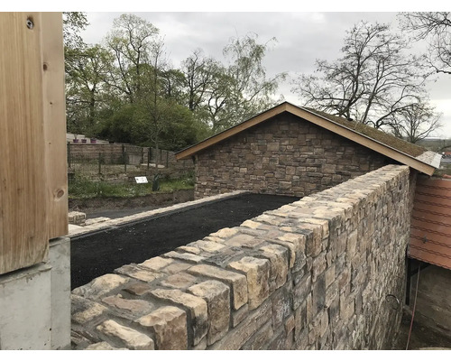 Venkovní fotografie budovy s kamennou zdí a zelenou střechou