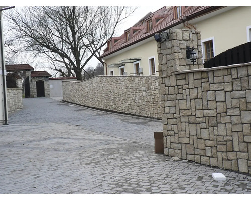 Venkovní fotografie dlouhé kamenné zdi podél dlážděné cesty