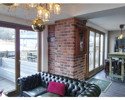 Interiér s koženou pohovkou, cihlovou zdí a dekorativním osvětlením