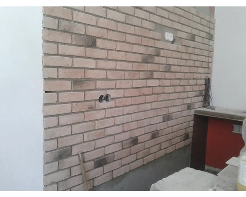 Stěna s obkladovými cihlami a zásuvkou