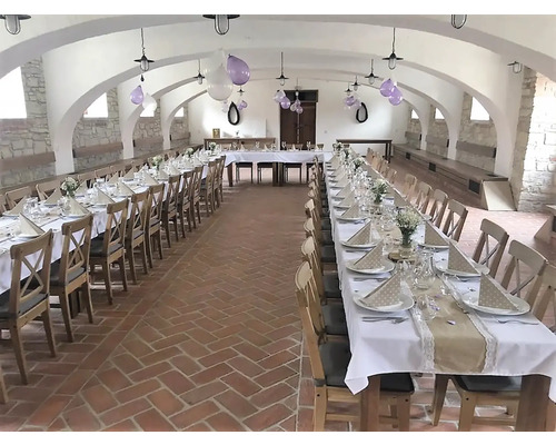 Vyzdobený sál s dlouhými stoly pro oslavu.