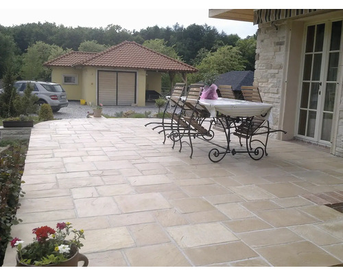 Venkovní prostor s kamennými dlaždicemi, zahradním stolem a židlemi