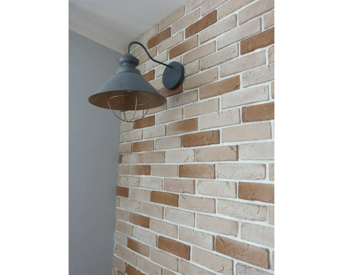 Nástěnné svítidlo s klecovým stínidlem na cihlové zdi