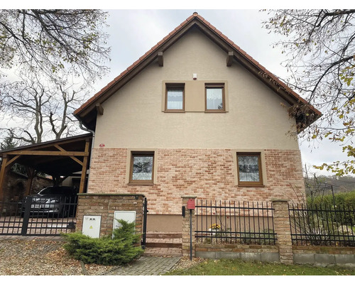 Pohled na dvoupodlažní obytný dům s cihlovým zdivem a sedlovou střechou