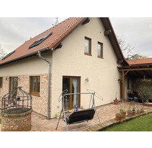 Vnější pohled na dům s cihlovou střechou, okny a dlážděnou terasou