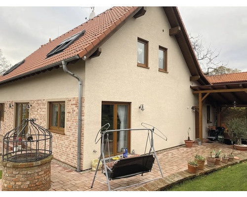 Vnější pohled na dům s cihlovou střechou, okny a dlážděnou terasou