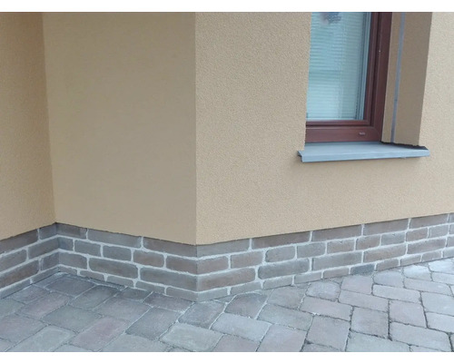 Venkovní pohled na dům s cihlovou patkou a dlažebními kostkami