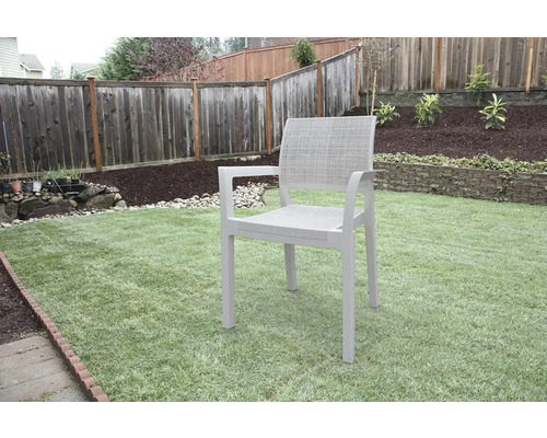 Zahradní scéna s jednou zahradní židlí na trávníku před dřevěným plotem