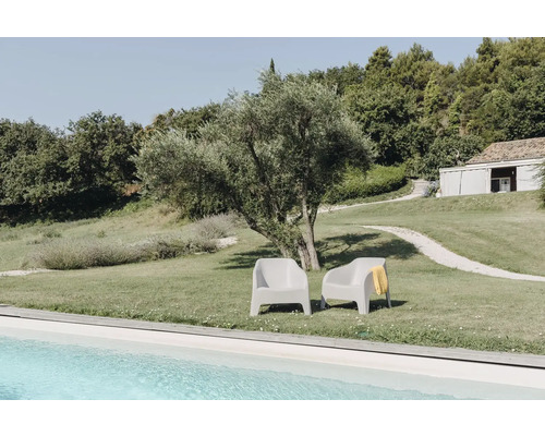 Dvě šedá plastová zahradní křesla na trávníku vedle bazénu.