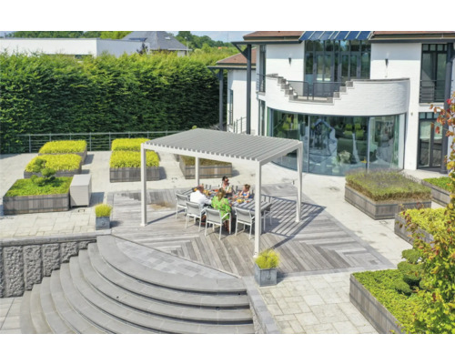 Rodina sedí pod terasovou střechou na dřevěné terase v zahradě.