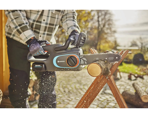 Osoba řeže dřevo pomocí akumulátorové řetězové pily Gardena na dřevěné koze