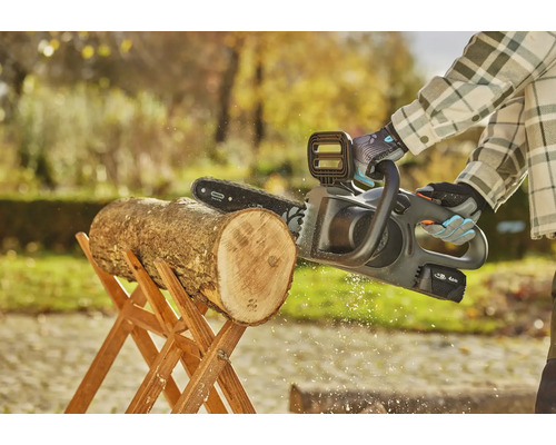 Akumulátorová řetězová pila řeže kládu na dřevěném koze