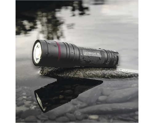 Černá svítilna Ultibright 70 leží na kameni ve vodě.