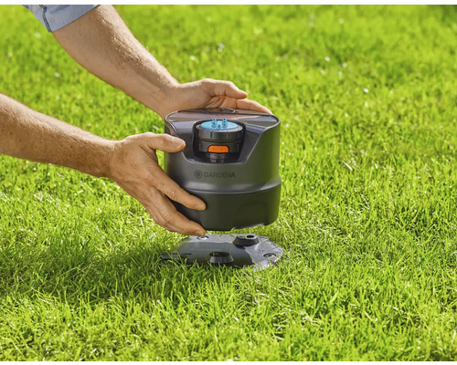 Čtyřplošný zavlažovač Gardena v trávníku, držený v rukou