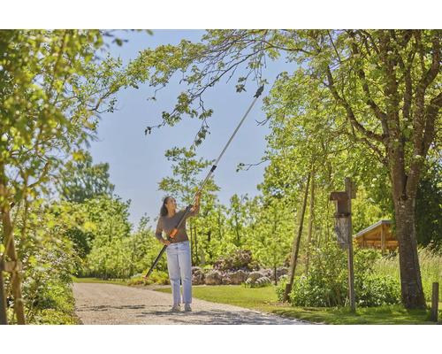 Žena používá nůžky na větve s teleskopickou násadou na zahradě k prořezávání větví