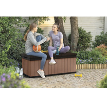 Dvě ženy sedí na hnědém plastovém úložném boxu na zahradě.