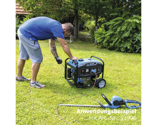 Uživatel spouští generátor na zahradě, nůžky na živý plot leží v trávě.