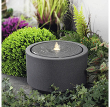 Kulatá pokojová fontána z kameniny s vodní hrou na zahradě.