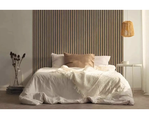 Ložnice s postelí před dřevěným lamelovým obkladem stěn, nočním stolkem a lampou