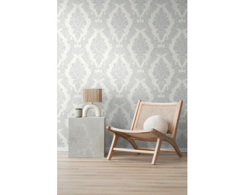 Pohled do místnosti s tapetou se vzorem, křeslem a odkládacím stolkem s lampou a rostlinou