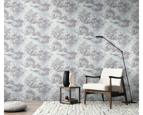 Pokoj s tapetou se vzorem oblaků, křeslem, stojací lampou a odkládacím stolkem.