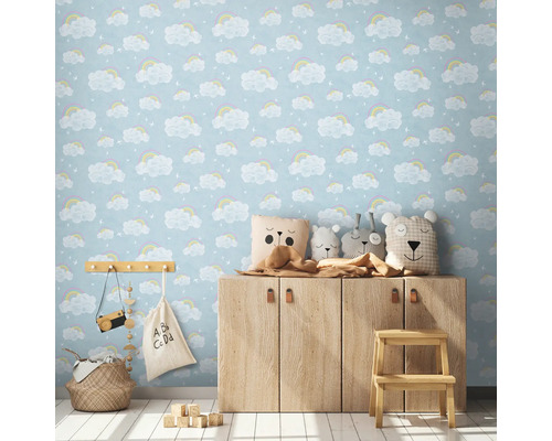 Dětský pokoj s tapetou s motivem oblaků a duhy, dřevěnou skříňkou a dekoracemi