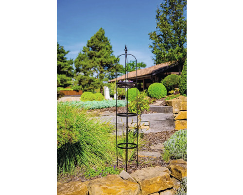 Kovová podpěra pro rostliny se třemi policemi na zahradě.