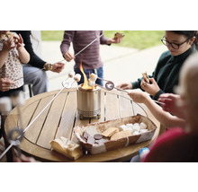Rodina opéká marshmallows na stolním grilu, na stole jsou přísady na s''mores.