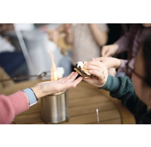 Lidé si připravují marshmallows nad stolním grilem, aby si udělali s''mores