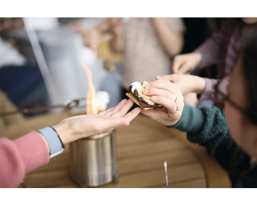 Lidé si připravují marshmallows nad stolním grilem, aby si udělali s''mores