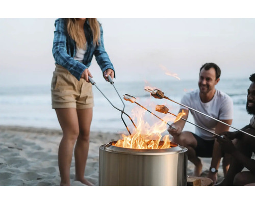 Lidé opékají marshmallows nad ohništěm na pláži.