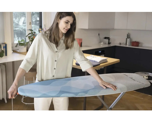 Žena umisťuje potah na žehlicí prkno