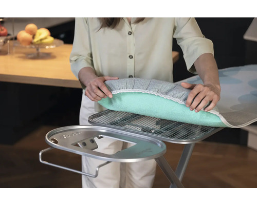 Žena pokládá potah na žehlicí prkno na žehlicí prkno