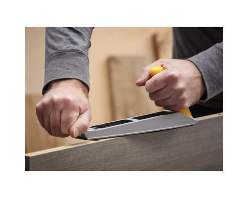 Osoba používá hoblík na opracování kusu dřeva.