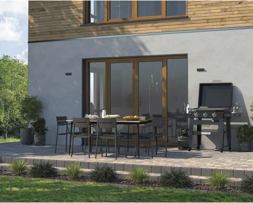 Terasa s grilem, zahradním stolem a zahradními židlemi před stěnou domu