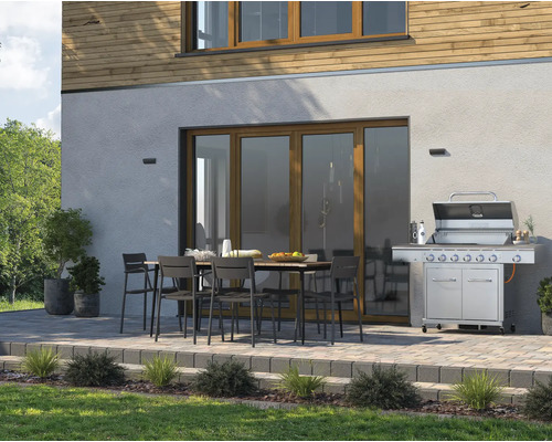 Terasa s grilem, zahradním stolem a židlemi před fasádou domu