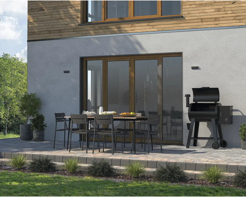 Venkovní posezení s jídelním stolem, židlemi a grilem vedle domu