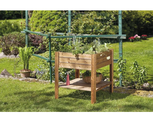 Dřevěný vyvýšený záhon s rostlinami a policí v zahradě