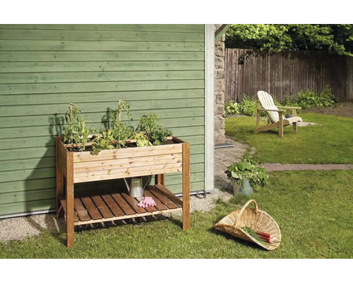 Dřevěný pěstební stůl s rostlinami a zahradním příslušenstvím v zahradě