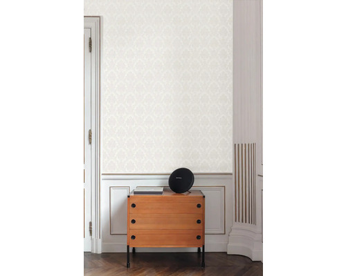 Scéna s komodou, reproduktorem a vzorovanou tapetou ve světlé místnosti
