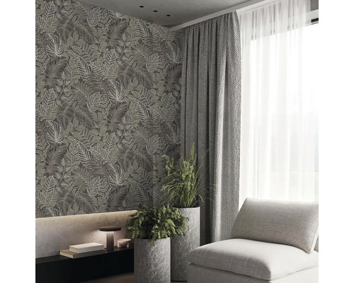 Moderní obývací pokoj s tapetou s motivem listů, závěsy, křeslem a pokojovými rostlinami v květináčích.