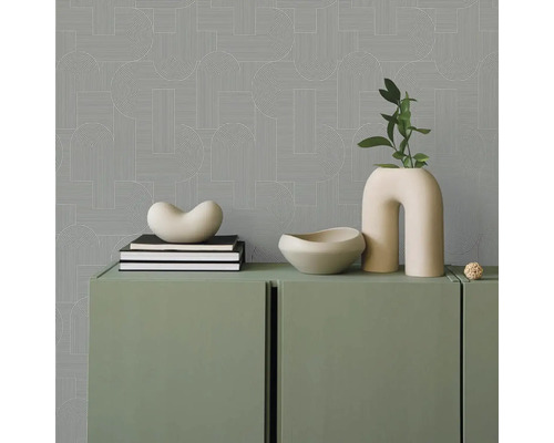 Pohled do místnosti s geometrickou tapetou, zelenou skříní a dekorativními předměty