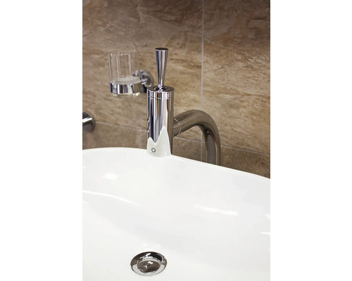 Snímek umyvadla s kovovou baterií a dávkovačem mýdla na zdi