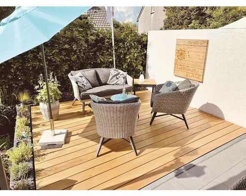 Zahradní scéna s ratanovým nábytkem, slunečníkem a dřevěnou terasou