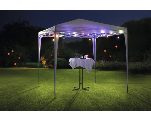 Pavilon se světelným řetězem a bistro stolem na trávníku