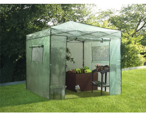 Skleník s rostlinami a zahradním stolem na zahradě